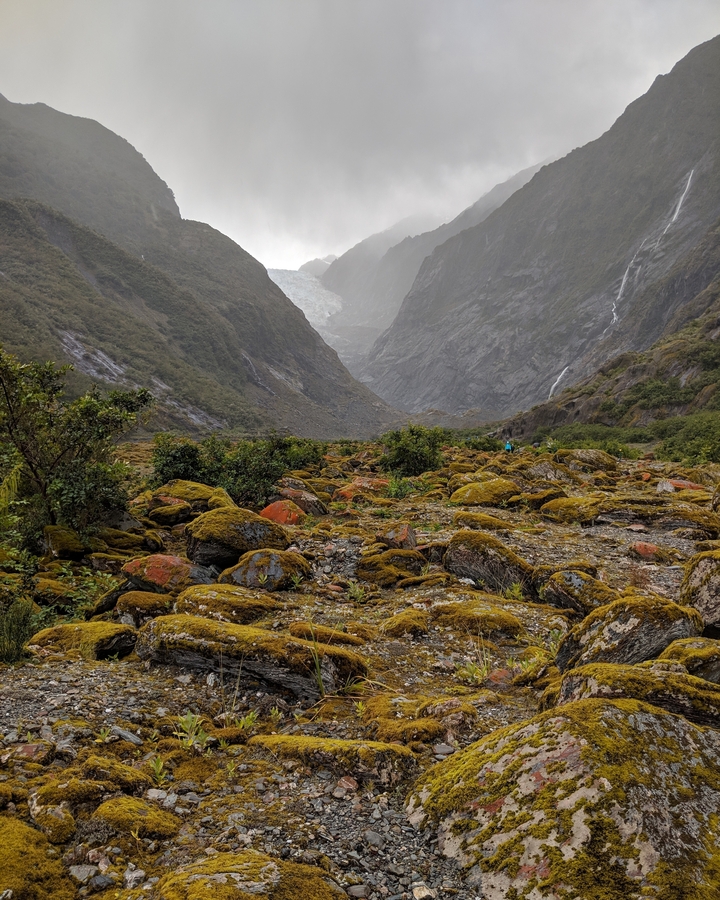 Paysage de montagne avec des rochers couverts de mousse et une cascade.