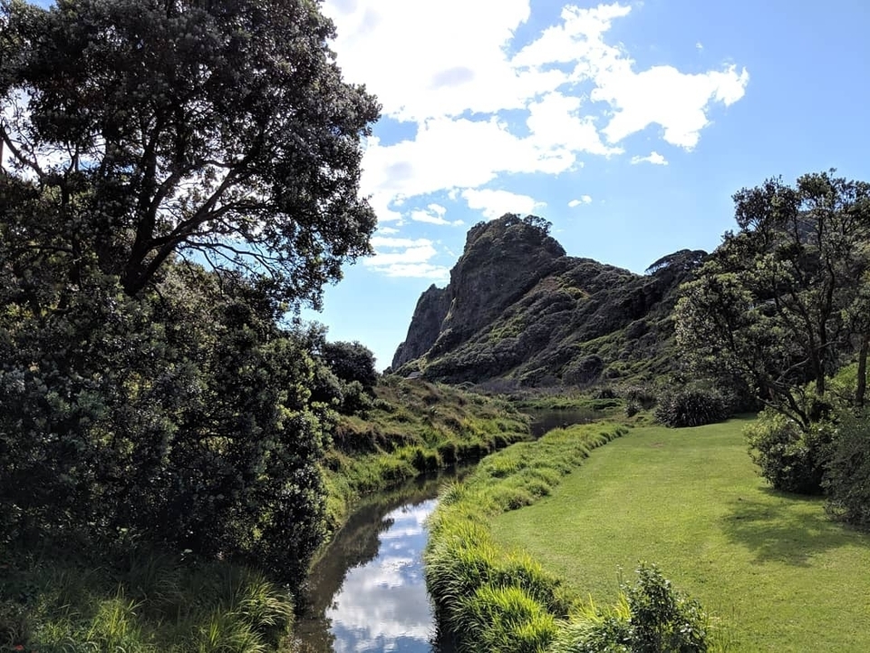 Lush landscape with a river and rocky hill.