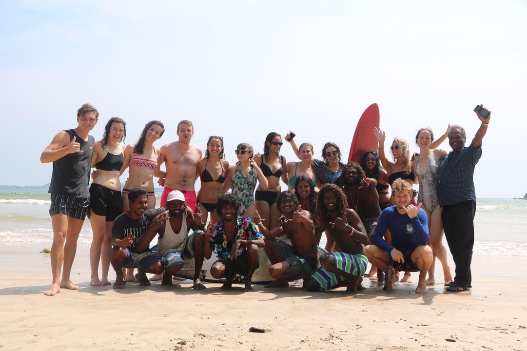 Groupe de personnes posant sur la plage avec des planches de surf.