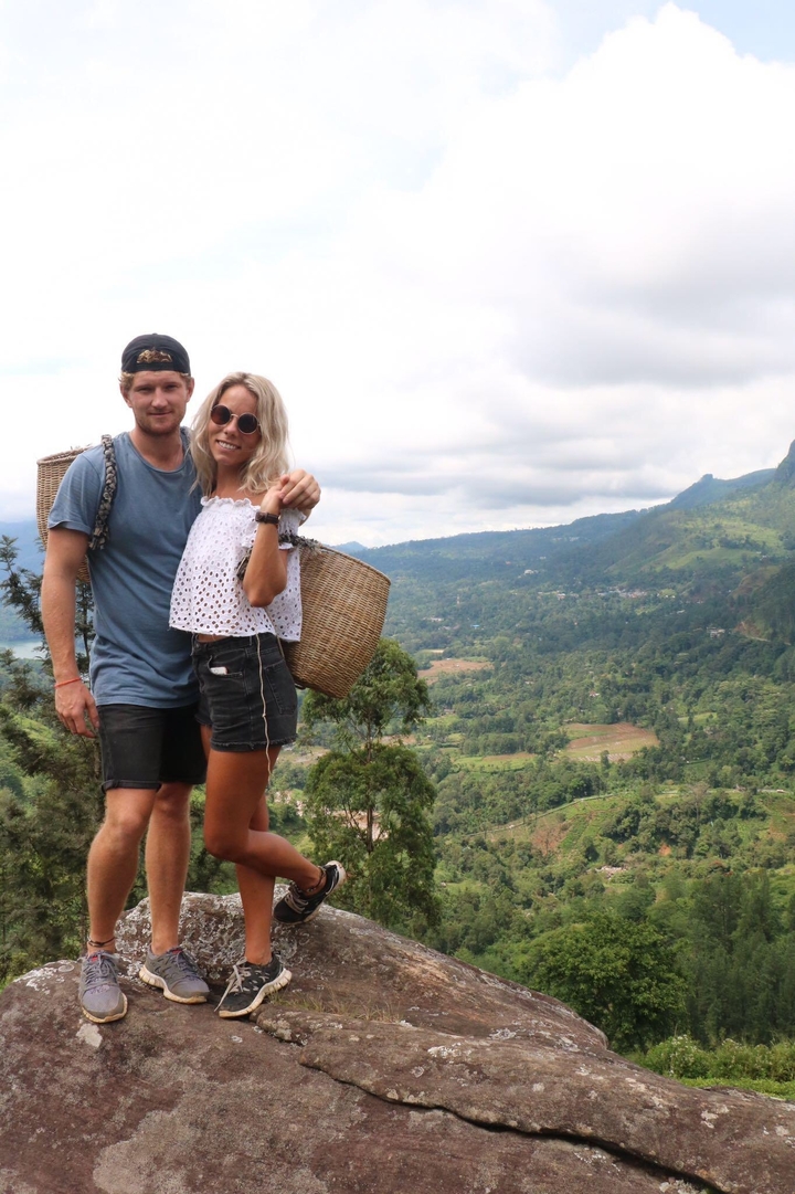 Couple avec sacs à dos debout devant une vue verdoyante.