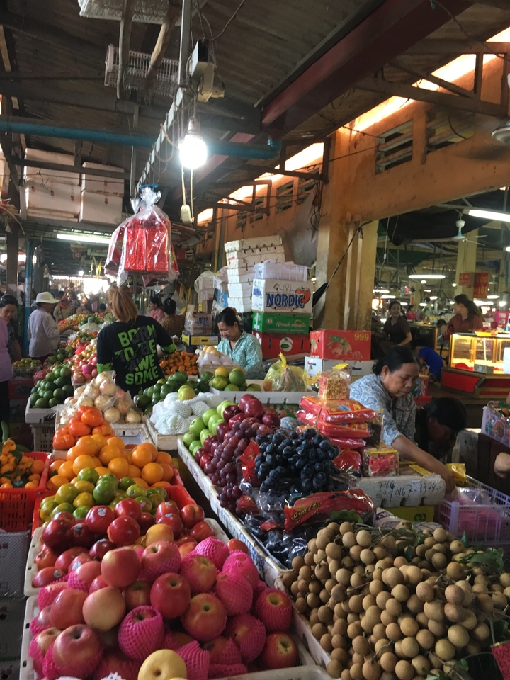 Une scène de marché animée avec des vendeurs et des produits colorés.