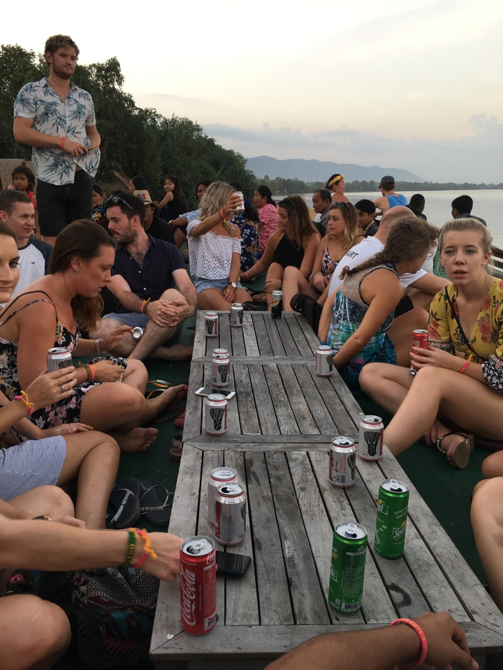 Un groupe de personnes qui socialisent sur le pont d'un bateau avec des boissons.