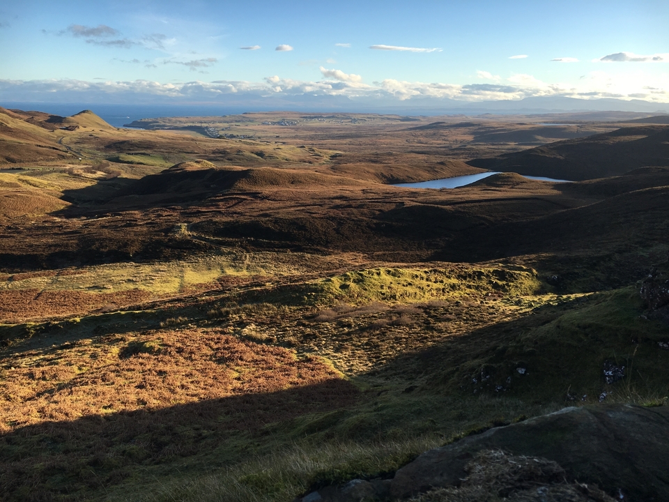 Vue étendue d'un paysage vallonné avec une grande étendue d'eau.