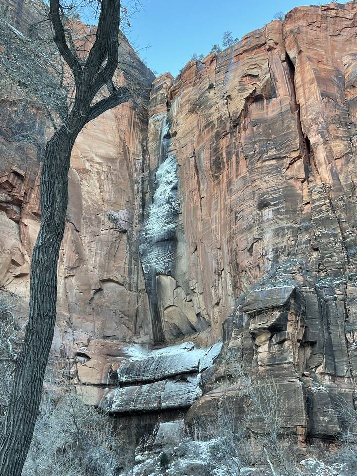 Grande falaise rocheuse avec plusieurs couches et plaques de neige.