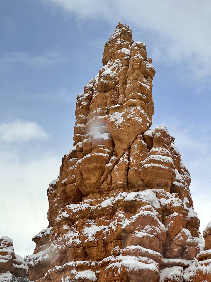 Formation rocheuse rouge saupoudrée de neige sur fond de ciel bleu.