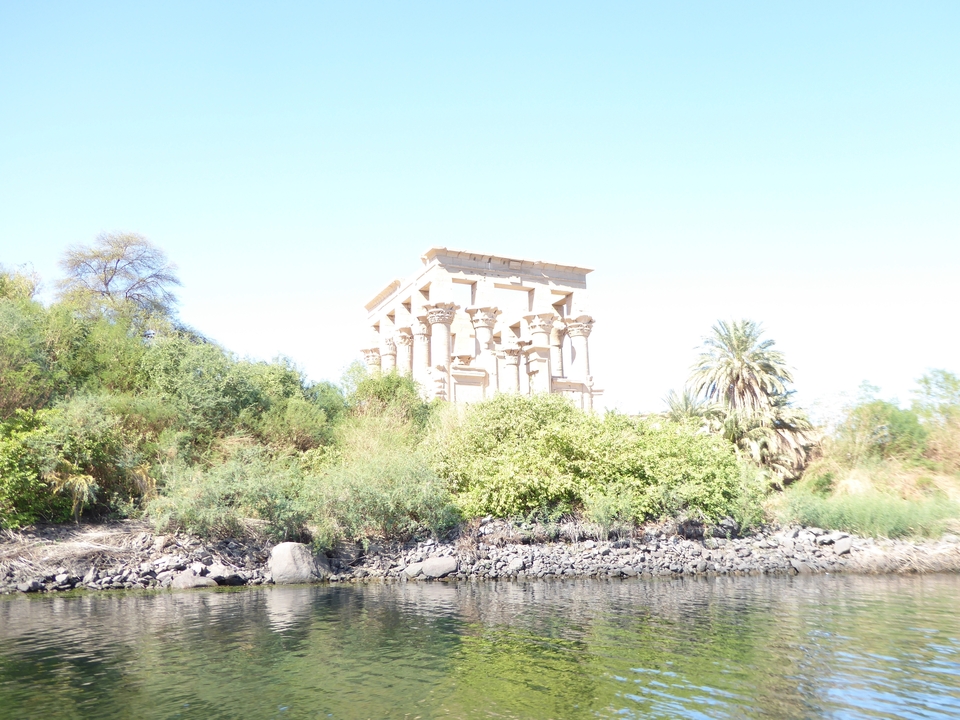 Ancien temple entouré de verdure au bord d'une rivière.