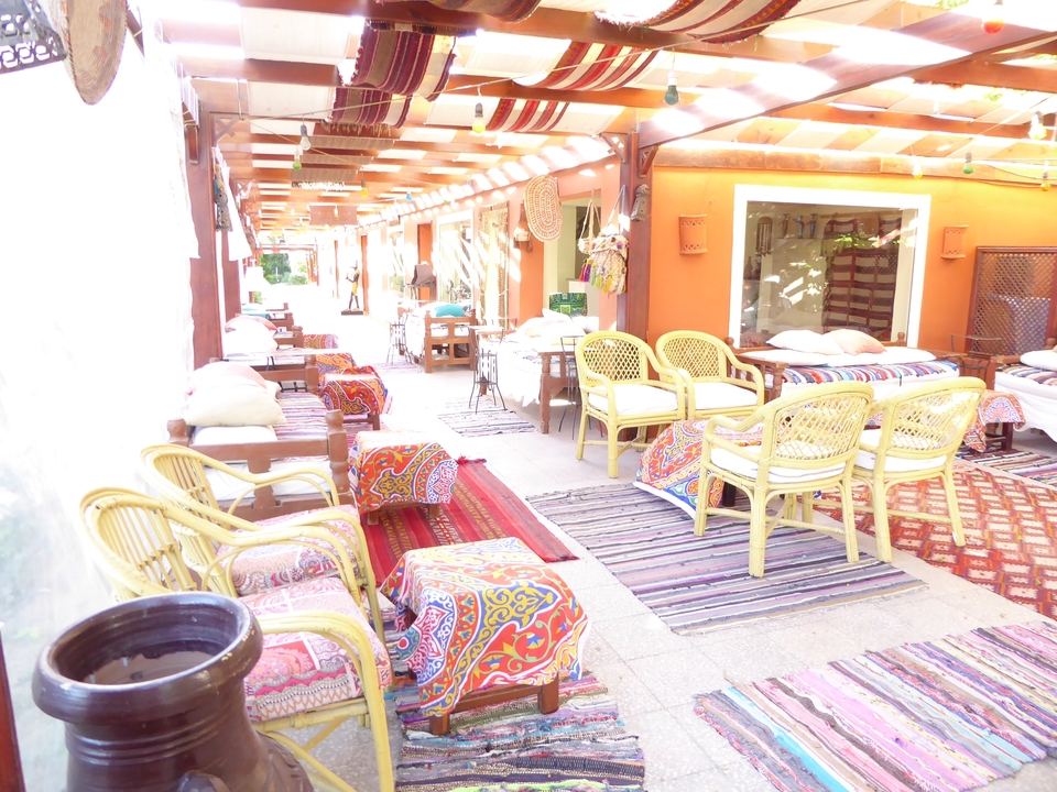 Restaurant ou café en plein air avec des coussins et des tapis colorés.