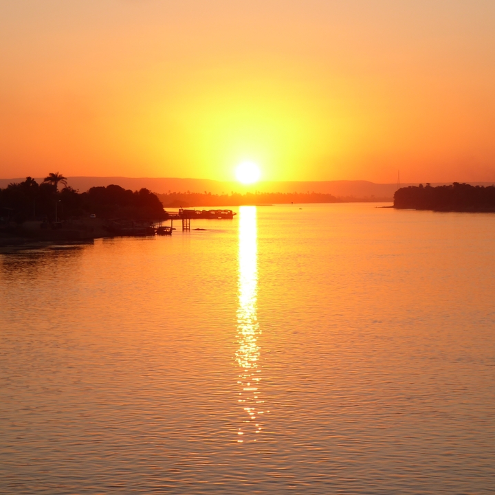 Coucher de soleil sur une rivière avec des arbres en silhouette