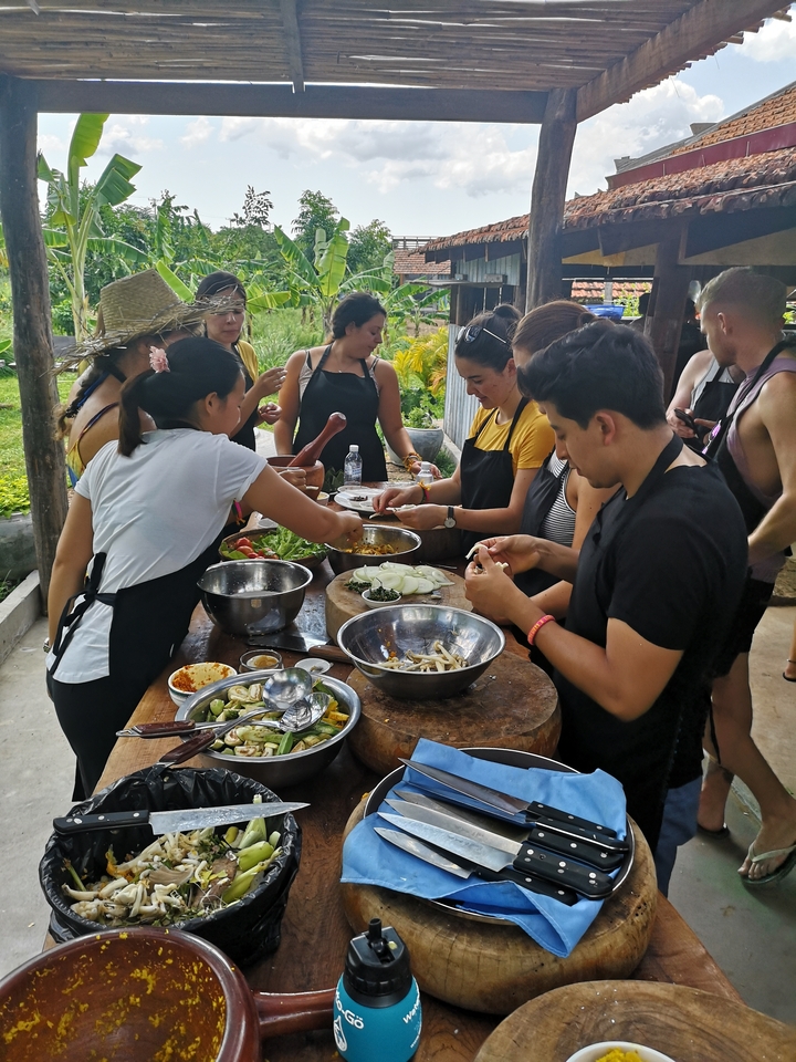 Des personnes participant à un cours de cuisine avec divers ingrédients sur la table.