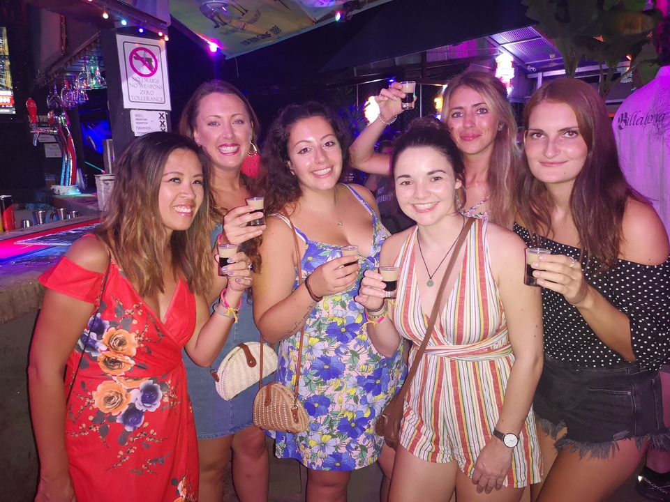 Groupe de femmes posant ensemble en tenant des boissons.