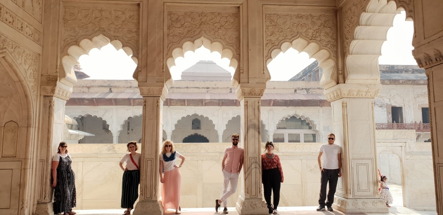 Des personnes posant sous des arches dans un bâtiment historique.