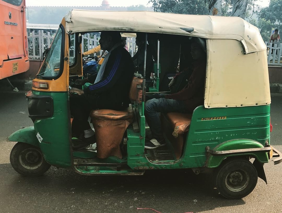 Un pousse-pousse automobile vert et jaune dans une rue.