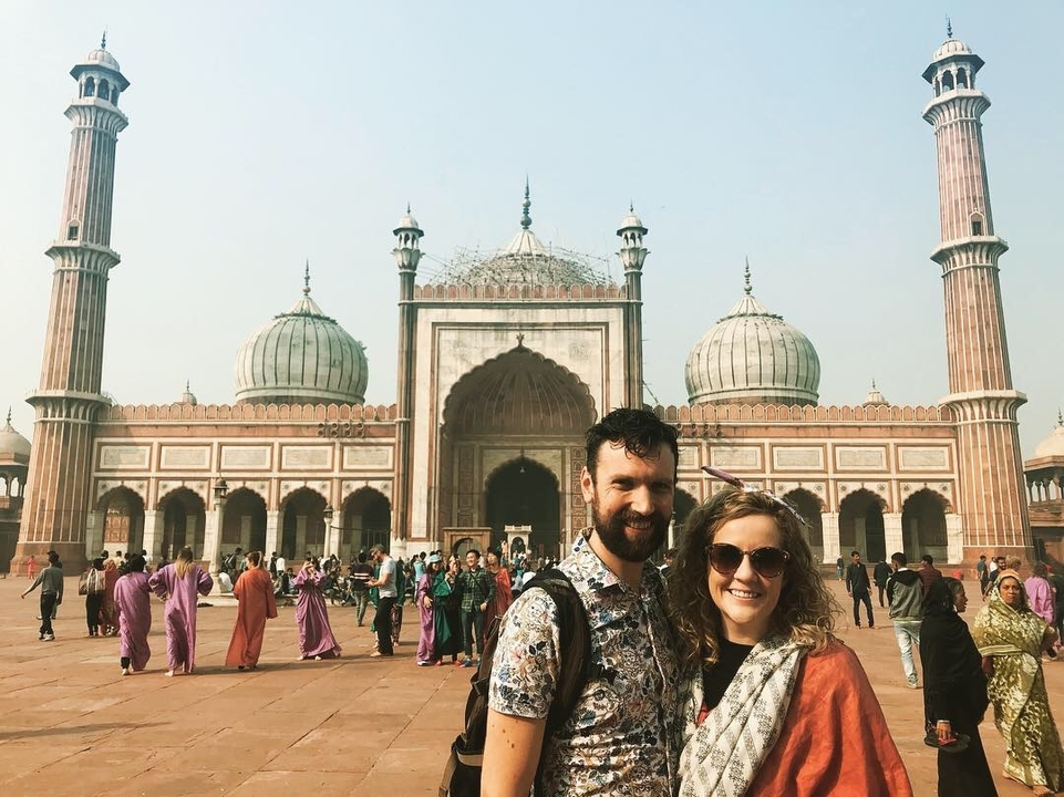 Un couple devant une mosquée emblématique.