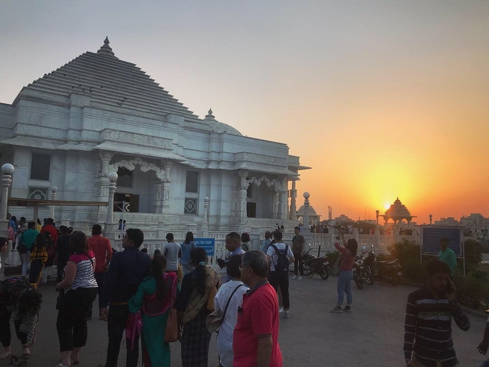 Vue du coucher de soleil d'un temple blanc avec des gens autour.