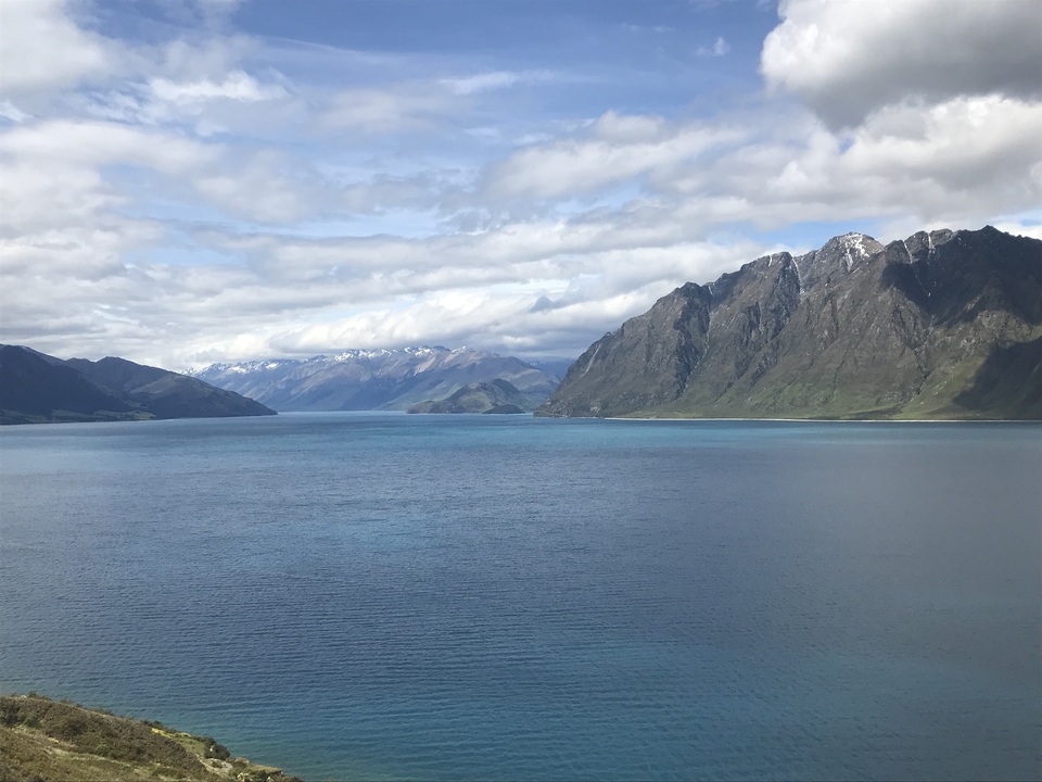 Lac pristine entouré de montagnes sous un ciel nuageux.