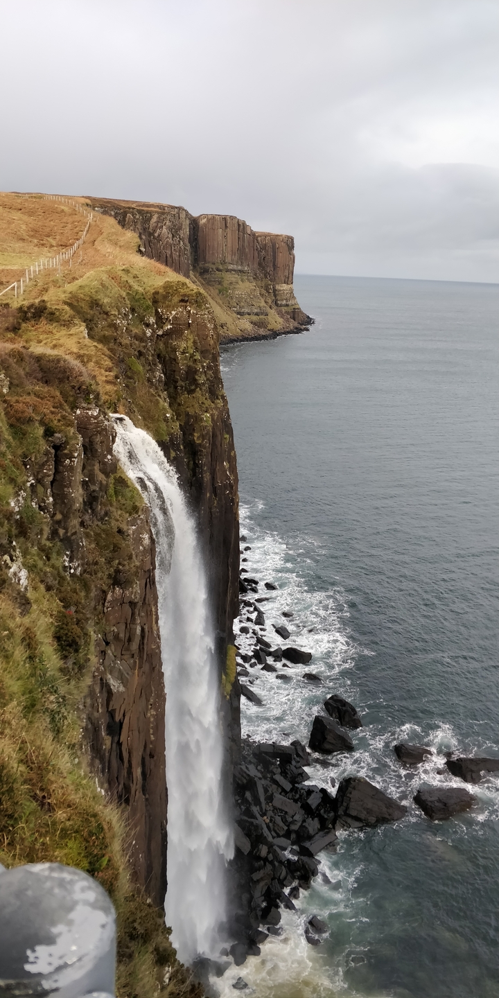 A waterfall cascading into the ocean along a cliff.