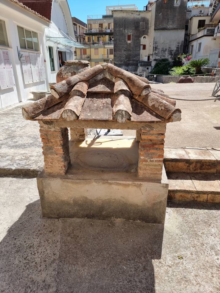 Structure de puits en pierre ancienne dans un cadre de ville historique.