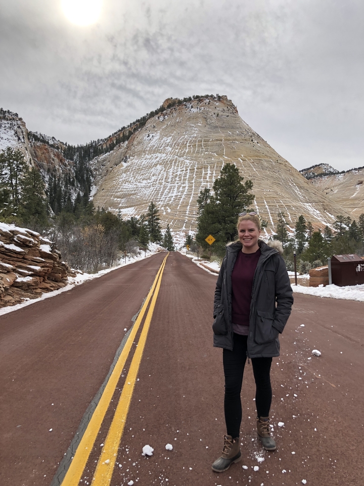 Personne debout sur une route déserte avec un paysage rocheux en arrière-plan.