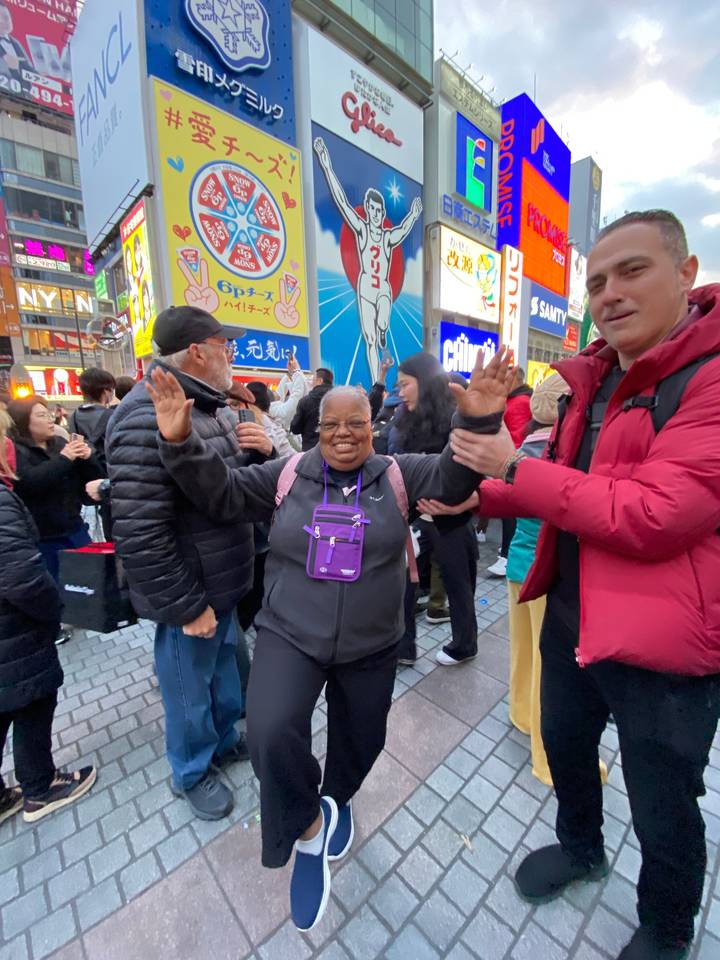 Des gens qui posent devant des enseignes lumineuses dans une rue de la ville.