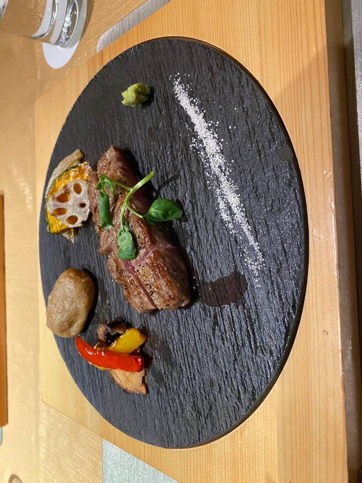 Plat gastronomique artistiquement dressé sur une pierre noire.