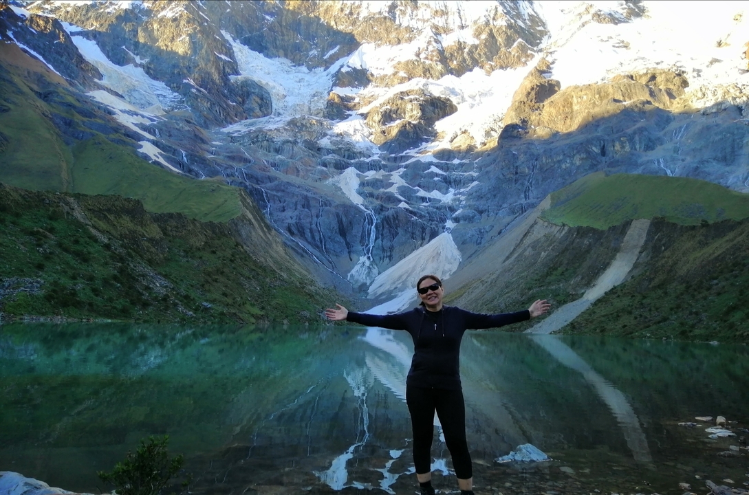 Une personne posant devant un magnifique paysage de montagne avec un lac.