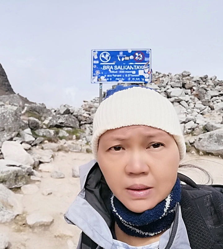 Gros plan d'une personne avec un panneau en arrière-plan indiquant le trek de Salkantay.