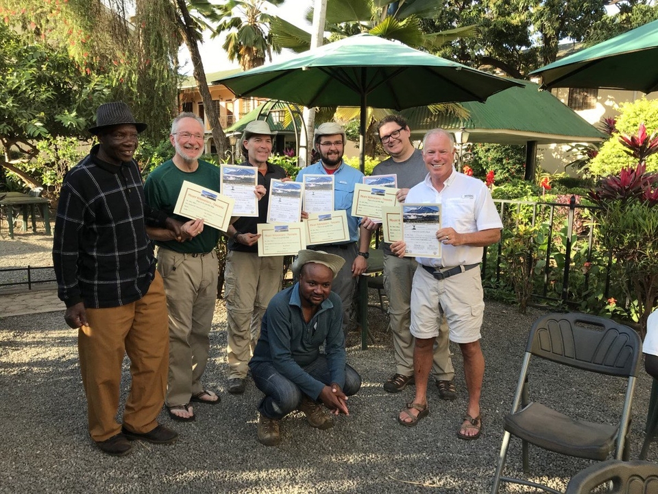 Groupe de personnes tenant des certificats, célébrant une réussite à l'extérieur.