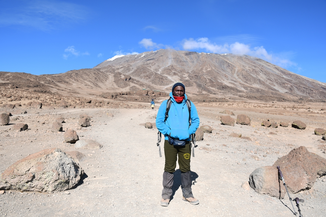 Personne posant devant un paysage de montagne avec un ciel bleu.
