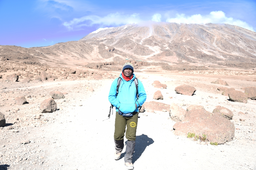 Personne posant dans un paysage lumineux avec une montagne.