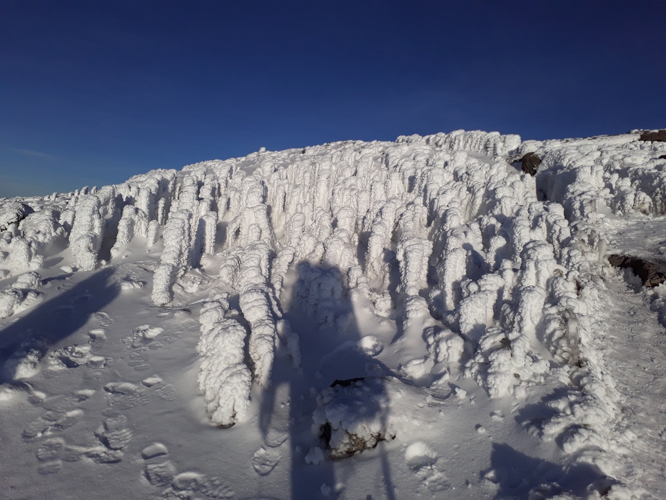 Pente rocheuse couverte de glace avec un ciel bleu dégagé.