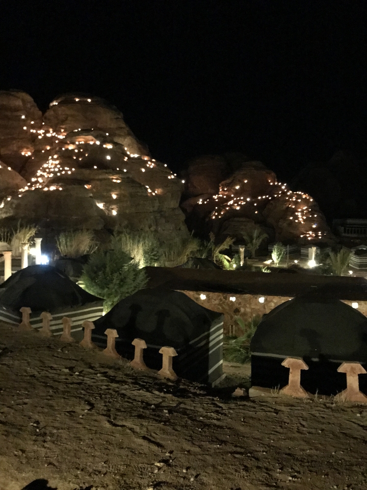 Nighttime scene with illuminated rock formations and campfire setting.