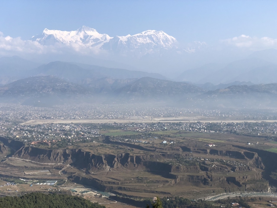 Vue aérienne d'une ville avec des montagnes en arrière-plan sous un ciel dégagé.