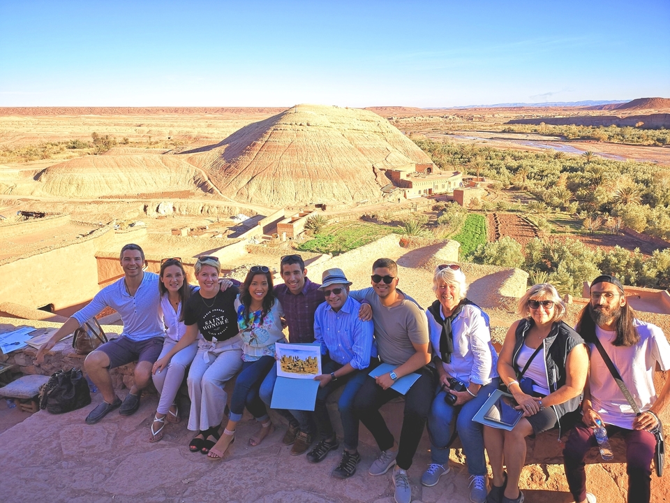 Groupe assis avec une vue panoramique sur une vallée et une colline en forme de dôme.