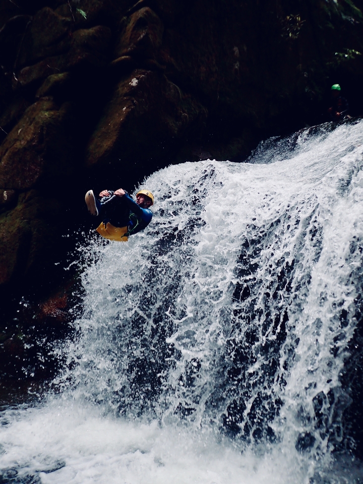 Homme en rappel le long d'une cascade en équipement d'aventure.