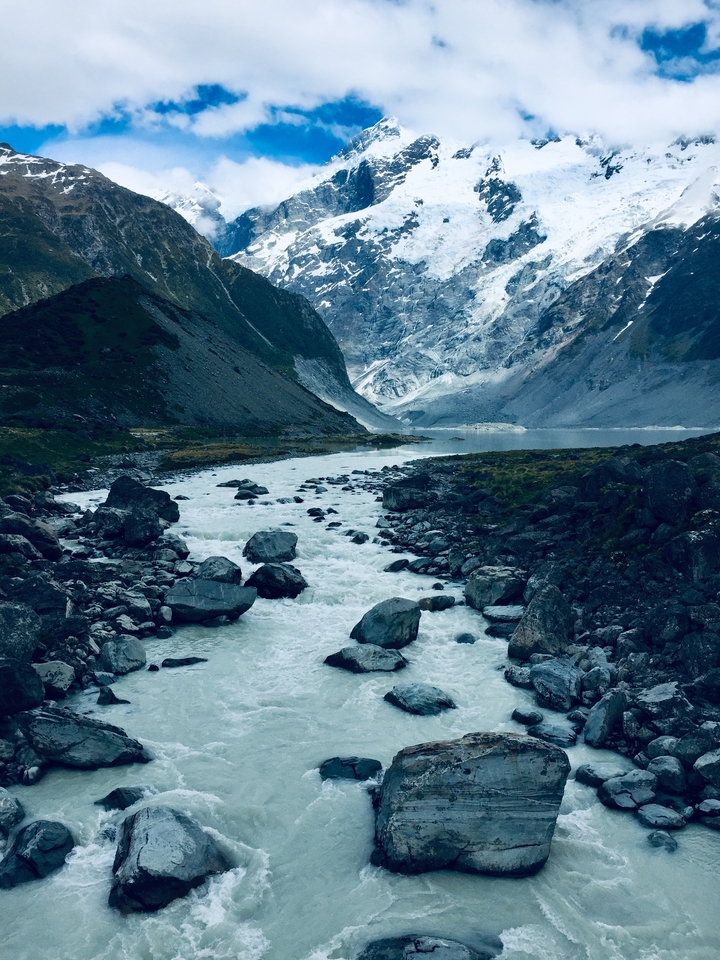 Rivière coulant à travers une vallée rocheuse avec des sommets enneigés.