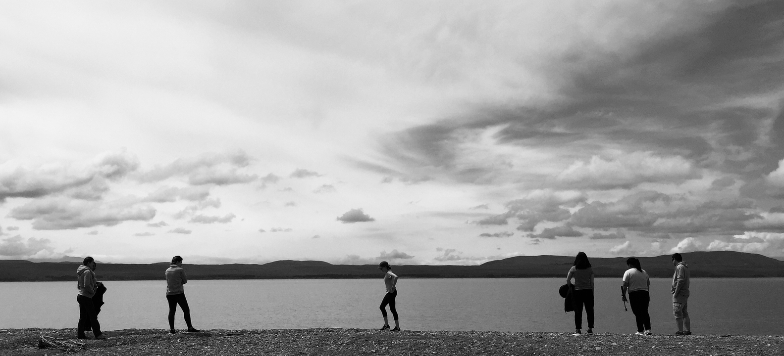 Des gens qui marchent le long de la rive d'un vaste lac.