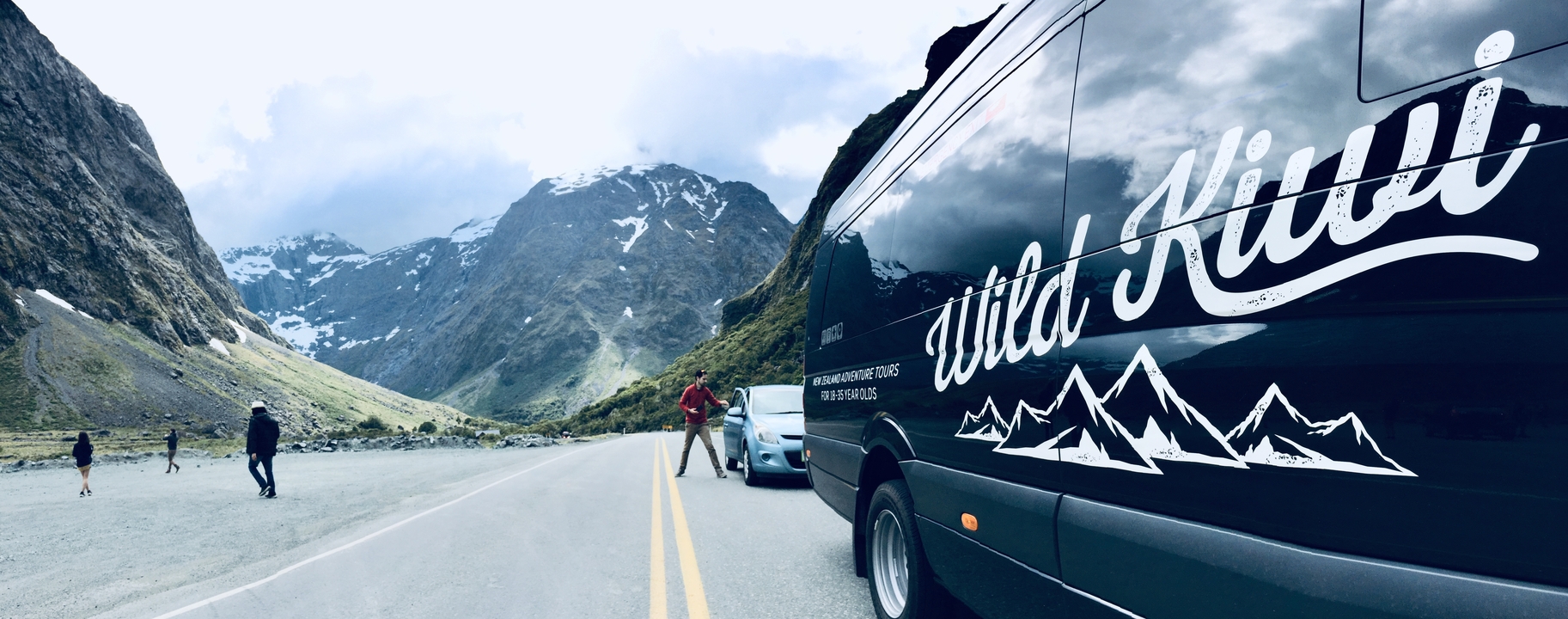 Homme posant avec une camionnette sur une route de montagne pittoresque.