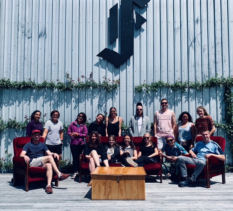 Groupe de personnes posant devant un bâtiment ressemblant à un entrepôt.