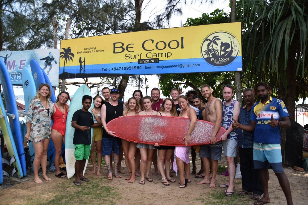 Groupe de personnes tenant une planche de surf dans un camp de surf.