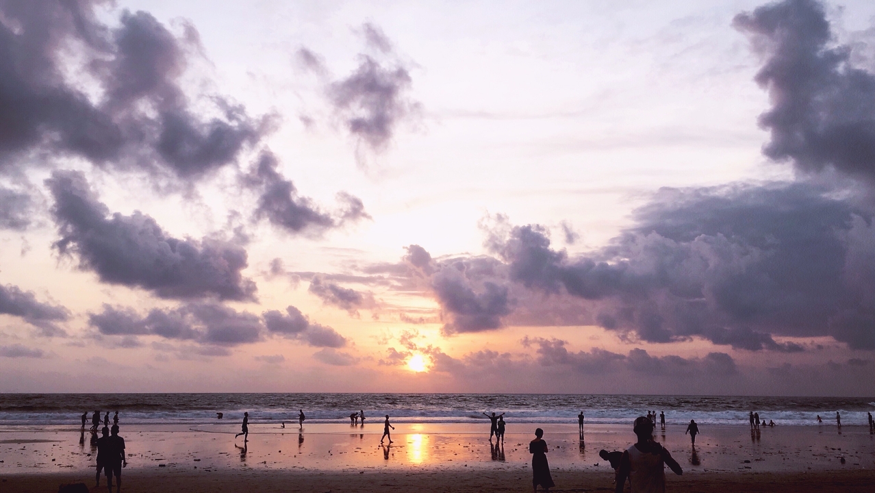 Plage au coucher de soleil avec des gens au loin.