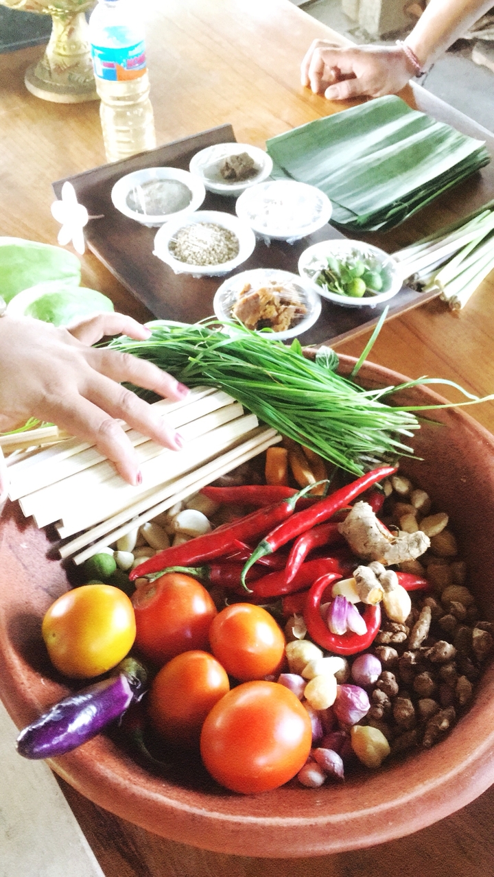 Personne tenant des épices et des herbes dans un bol, préparant de la nourriture.