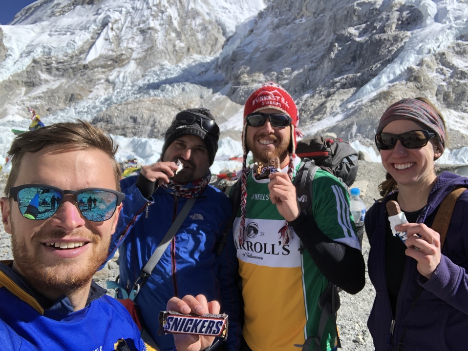 Quatre personnes savourant des collations avec un glacier montagneux en arrière-plan.