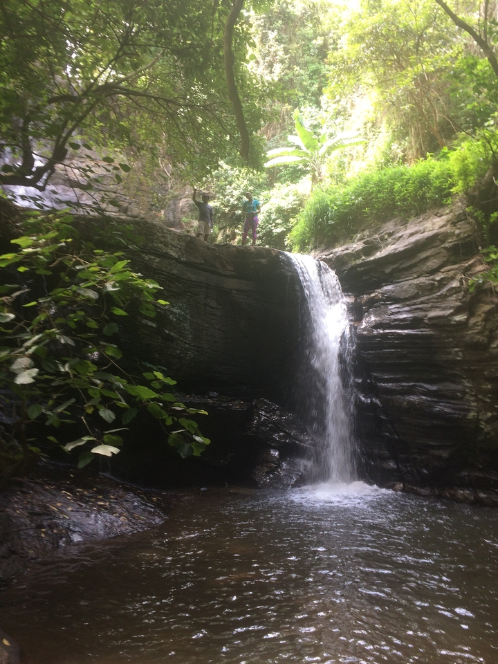 Cascade qui dégringole le long d'une falaise rocheuse avec des gens au sommet.