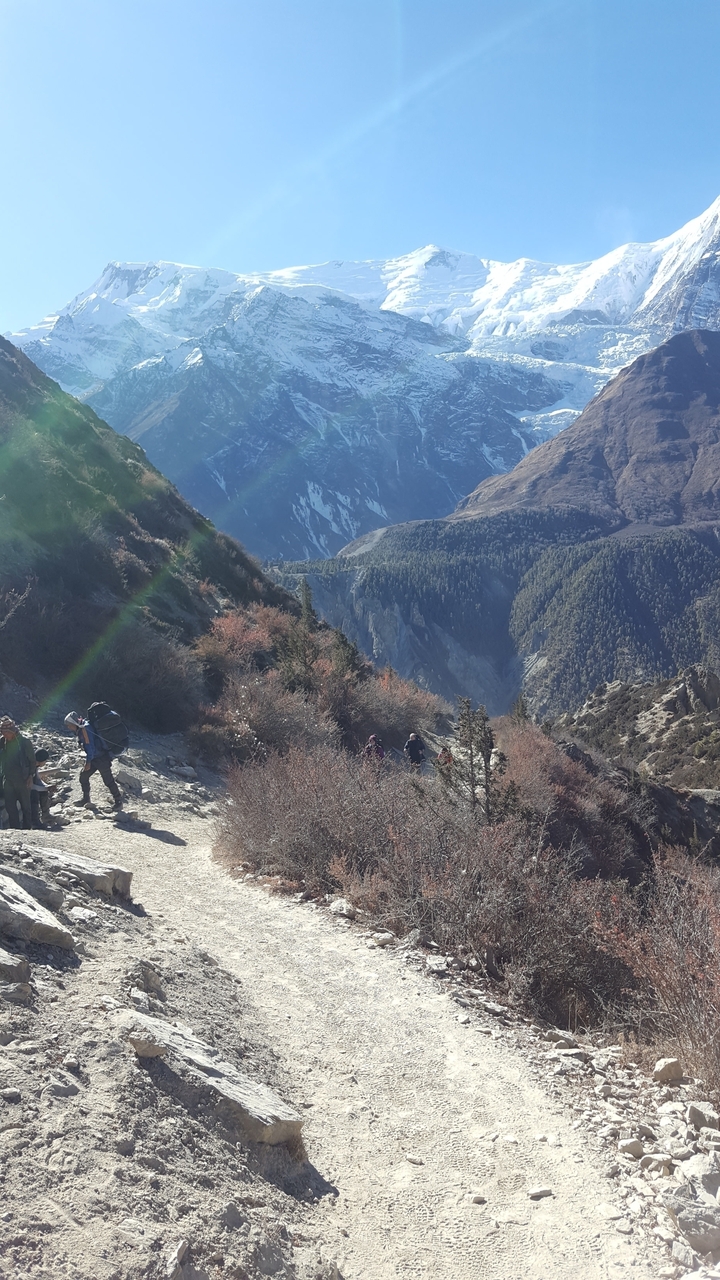 Randonneurs sur un sentier dans les montagnes avec un paysage pittoresque en arrière-plan.