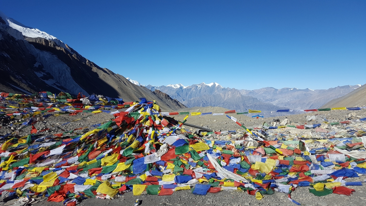 Drapeaux de prière colorés dans les montagnes avec des sommets enneigés en arrière-plan.