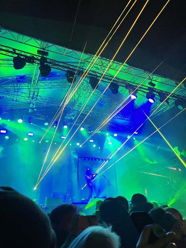 Concert avec éclairages laser et spectateurs regardant la scène.