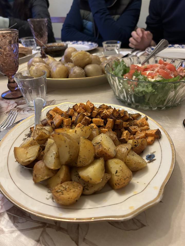 Plateau de légumes rôtis et salade sur une table avec des personnes.