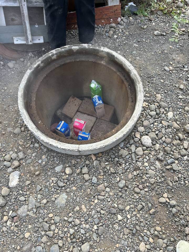 Bassine avec des cartons de lait sur une surface de gravier.