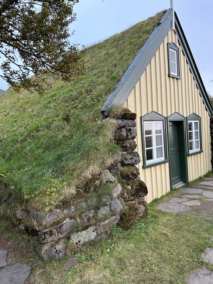 Maison avec un toit de gazon dans une zone herbeuse.