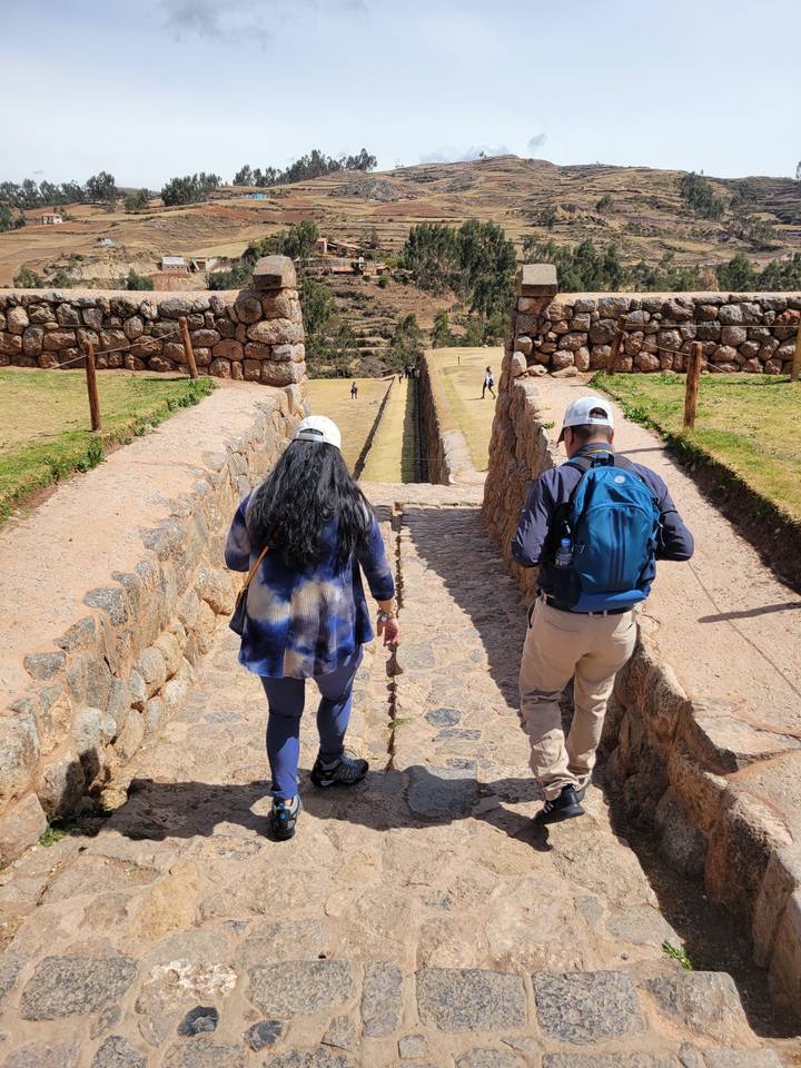 Deux personnes marchant sur un sentier de pierre dans une région vallonnée.